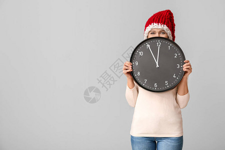圣诞倒计时概念圣塔帽和有钟表的年轻女图片