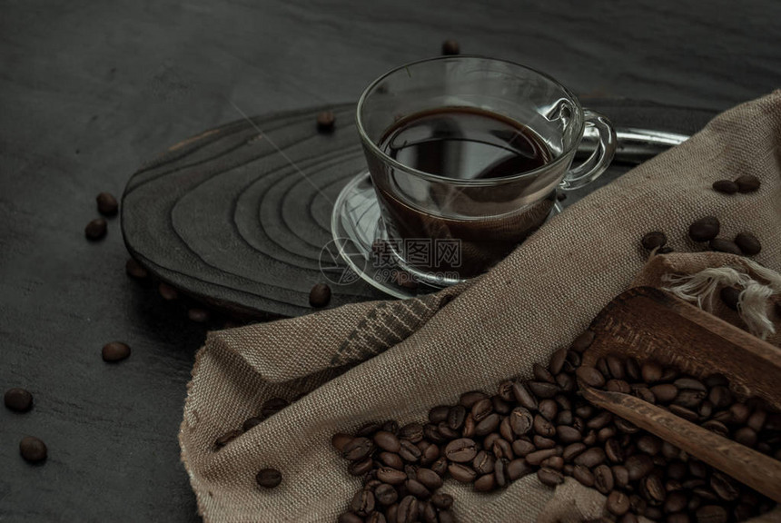 一杯咖啡和咖啡豆在木制和深色的石头背景上旋转着旧木勺和咖啡豆图片