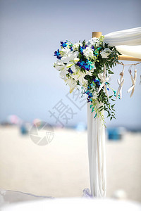 在沿海沙滩上装饰蓝白鲜花和海星的外门婚图片
