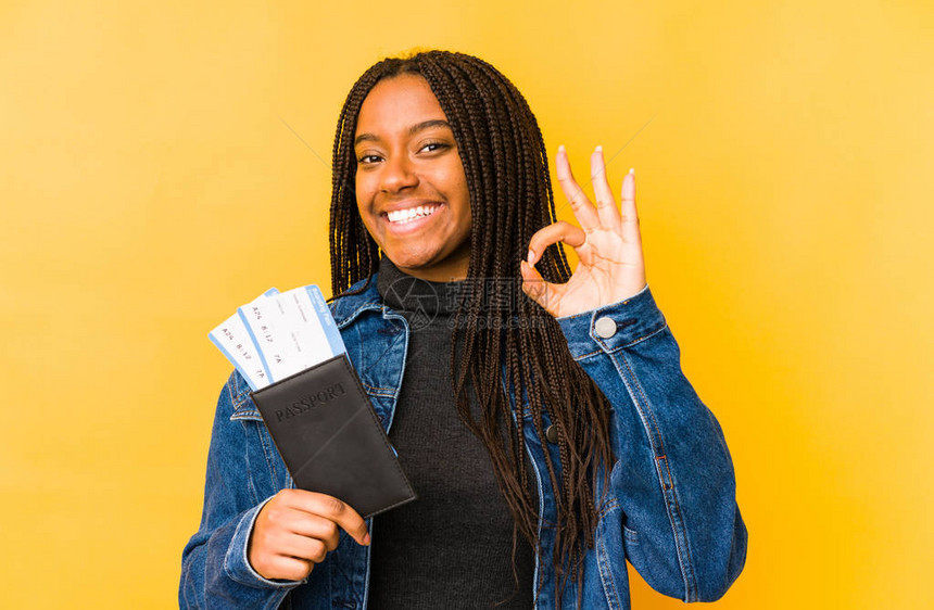 持有护照的年轻非裔美国妇女孤立欢乐和自信地表现出了正确的姿态图片