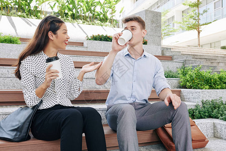 坐在长椅上喝酒咖啡在休息时讨论新闻的生意图片