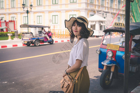 身戴帽子的亚裔女与泰国TukTuk马图片