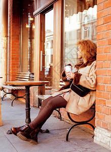 年轻漂亮的非洲裔美国女在咖啡馆外喝咖啡图片