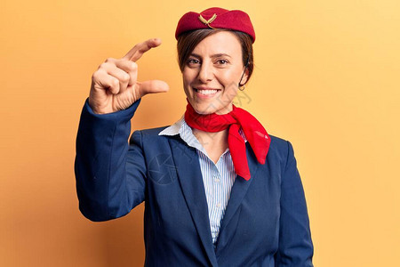身穿空姐制服的年轻美女笑着满怀自信地用手做小标志图片