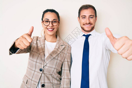 穿着商业服装的漂亮夫妇同意用手做积极的姿态笑着大拇指图片