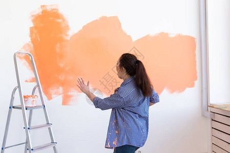 快乐的年轻女子在她的新公寓里画墙图片