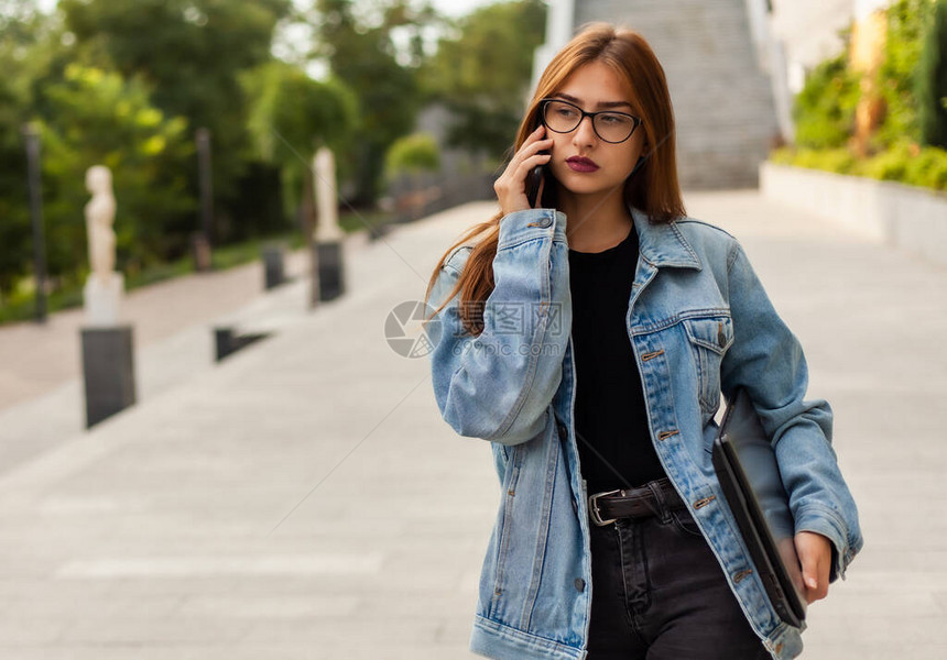 年轻时尚的女人穿着牛仔夹克和眼镜图片