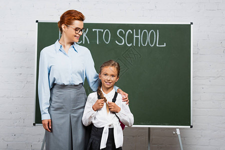 快乐的老师和女学生站在黑板旁边背图片