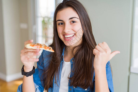 漂亮的年轻女人吃着一片美味的比萨饼图片