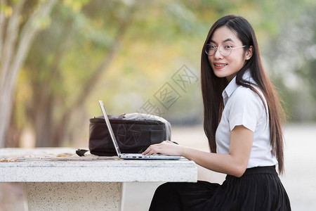 年轻的亚洲女大学生坐在大学校园的长凳上打字笔记本电脑女大学生上大学回图片