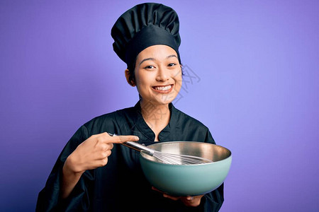 年轻漂亮的厨师女人穿着炊具制服和帽子图片