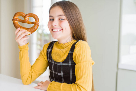 漂亮的小女孩吃着德国小吃咸椒盐卷饼图片