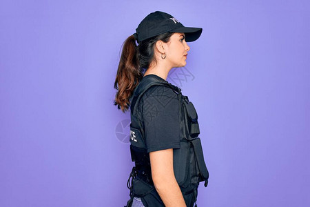 身穿紫色背景防弹衣的年轻女警察穿着安全防弹背心制服图片