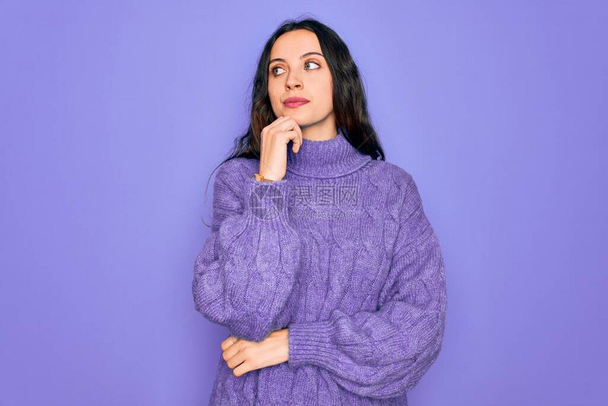 年轻漂亮的女人穿着休闲高领毛衣站在紫色背景上图片
