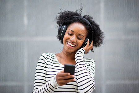 以手机和耳机收听音乐的非洲年轻女光耀着快图片
