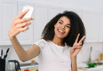 快乐美丽的非洲裔美国女人在手机摄像头上自拍图片