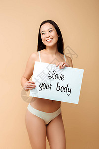 喜悦的亚裔女孩拿着标语牌爱着你的身体在蜜蜂图片
