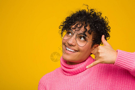 身穿粉色毛衣的年轻非洲裔美国妇女用手指展示图片