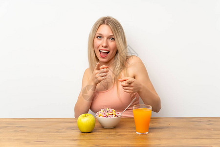 年轻的金发年轻女人吃早餐的尖图片