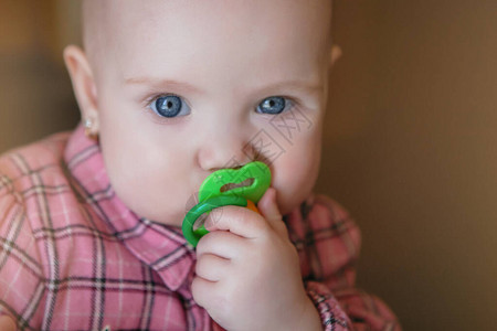 一个蓝眼睛的女婴手上拿着一个奶嘴还有一件粉红图片