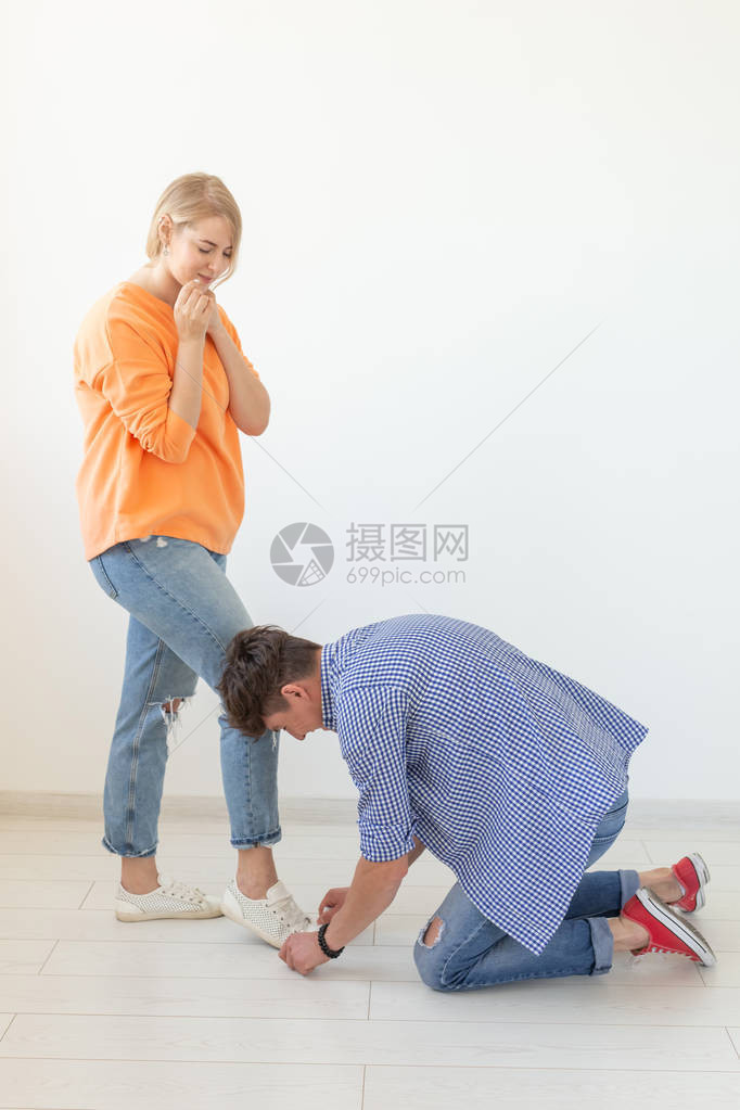 年轻男子用他深爱的女人的鞋带绑在白色背景上求偶和尊贵关系的概念广告图片