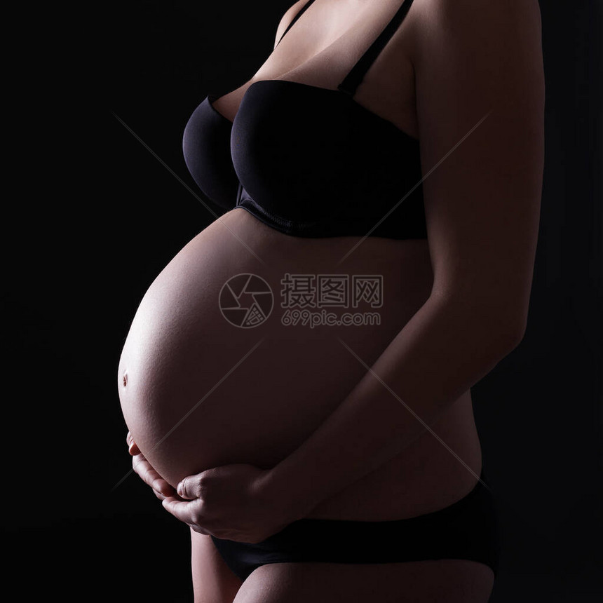 黑色背景下怀孕女身体的特写图片