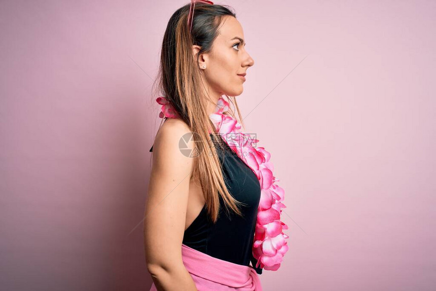 穿泳衣的金发年轻女子穿着鲜花夏威夷礼服身穿粉红色背景图片
