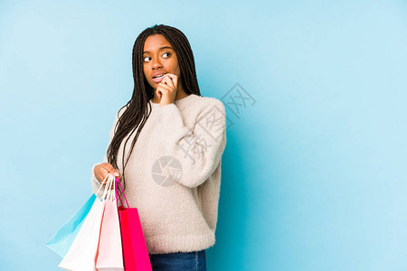 年轻非裔美国女人拿着一个购物袋孤立地放松着想一些东西在寻找复制空间图片