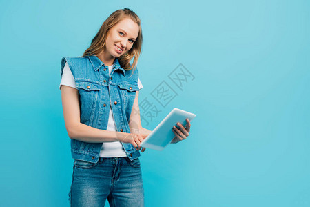 戴尼姆服装的年轻妇女使用数字平板电脑图片