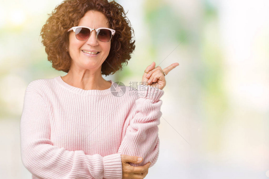 美丽的中年高级女穿着粉红色的毛衣和太阳镜图片