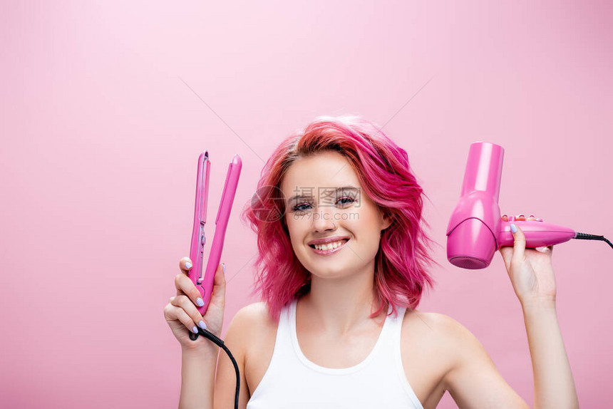 头发五颜六色的年轻女子拿着直发器和吹风机图片
