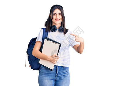 身着学生背包的年轻漂亮女孩拿着笔记本图片