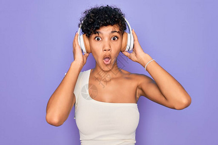 漂亮的非洲裔美国女用红色背景的耳机听音乐图片