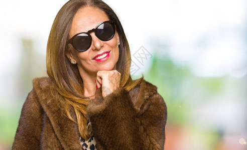 美丽的中年优雅女人戴着墨镜和貂皮大衣图片