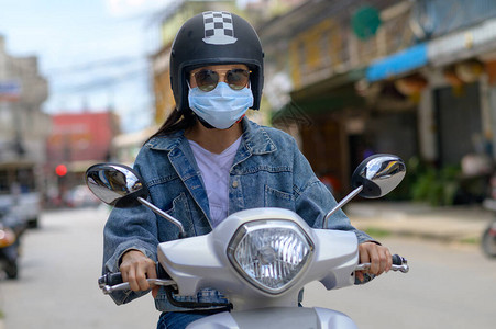 妇女骑摩托车在城里戴图片