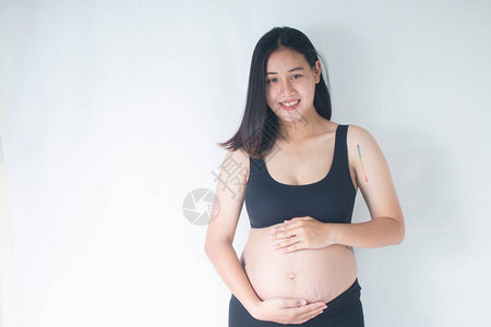 微笑的孕妇站着抱着她的肚子图片