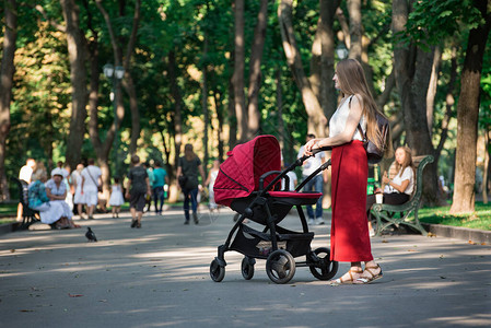 夏日公园的年轻美丽的母亲和婴儿床幸福的母亲概念图片