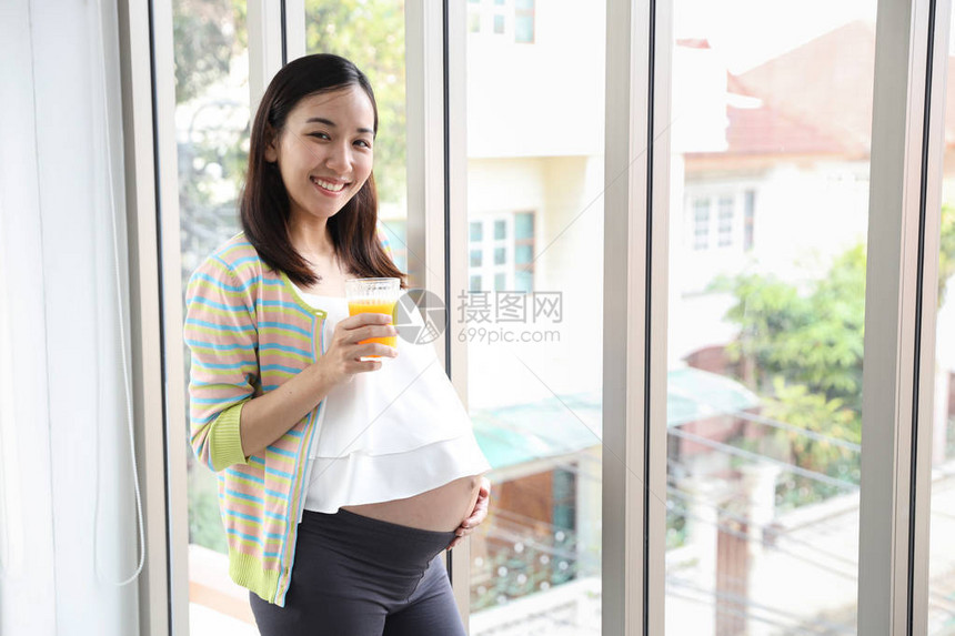 怀着一杯水保健概念时对怀孕的肚子微笑图片
