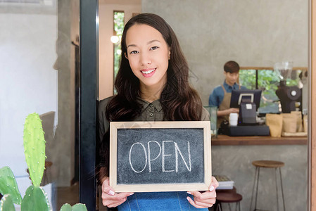 年轻亚洲女企业家在咖啡店前门露头牌的亚洲青图片