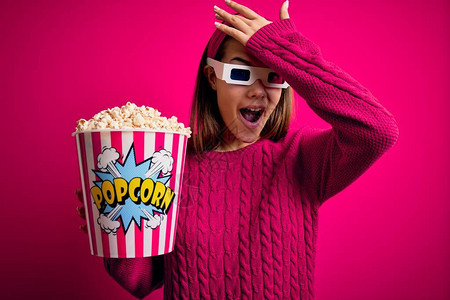 年轻漂亮的女孩用3D眼镜吃爆米花的盒子看电影图片