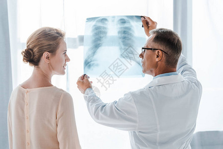 穿白色大衣的医生和在诊所内靠近X光镜图片