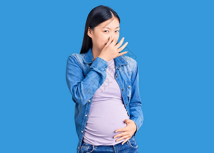 年轻美丽的女人怀孕期待婴儿闻到臭味和恶心图片