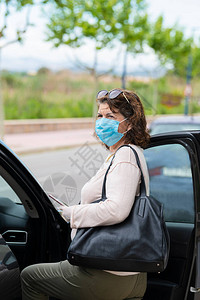 一个戴着防护面具和手套的女人进入他的车流行病概图片