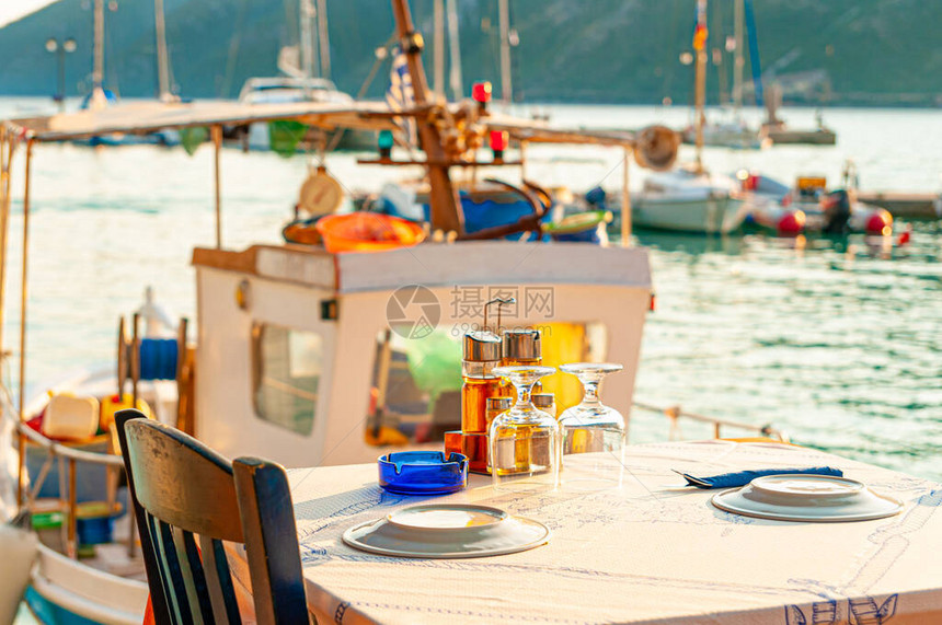 希腊列夫卡达瓦西里基湾海边一家餐馆的餐桌和一艘图片