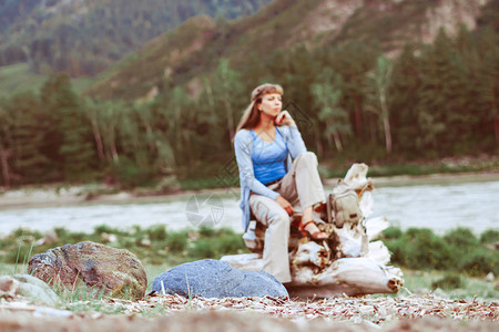 女孩坐在河边的石头上看着风图片