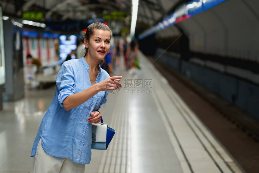 地铁里的女人在火车站的月台上等待火车到达图片