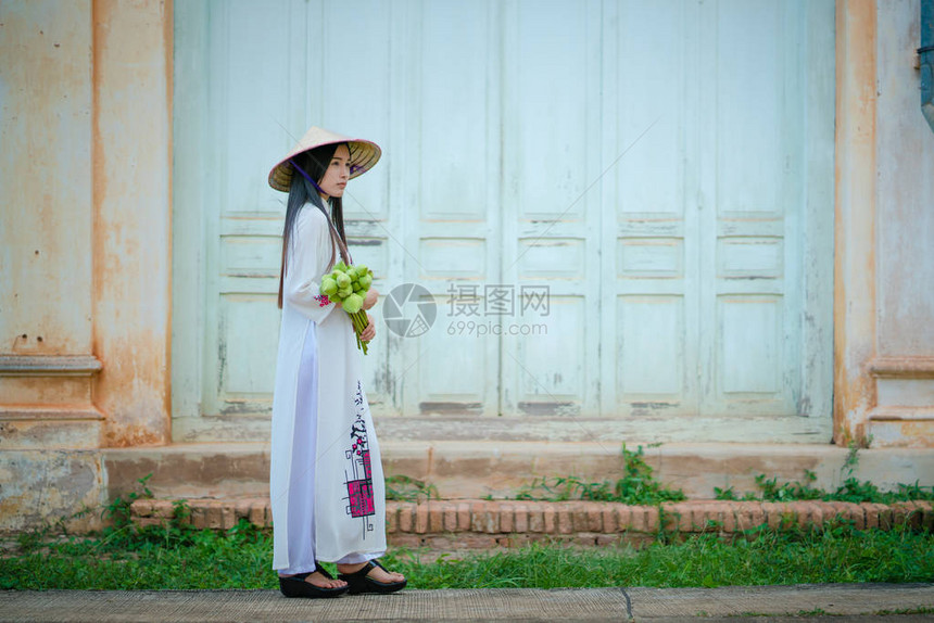 穿着越南传统文化礼服AoDai和握着莲图片