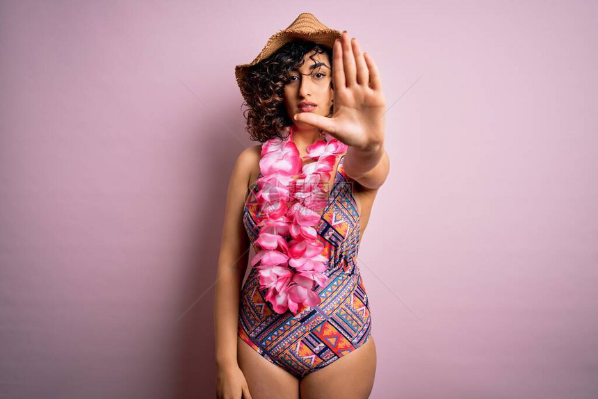 身着泳衣和哈瓦伊亚莱花朵的年轻美丽的阿拉伯女度假时图片