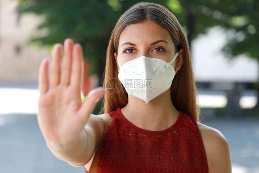 停止COVID19戴KN95FFP2面罩的年轻女子脸上显示手势停止在户外看相机戴面罩的女孩在镜头前张开手掌图片