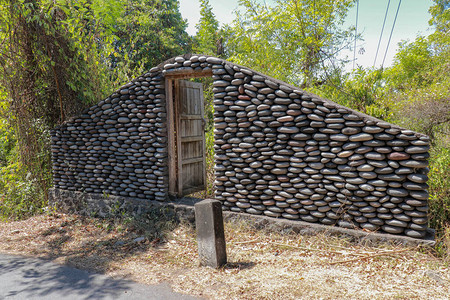 路边有封闭的旧木门的石墙丛林中的鹅卵石墙河里的石头图片